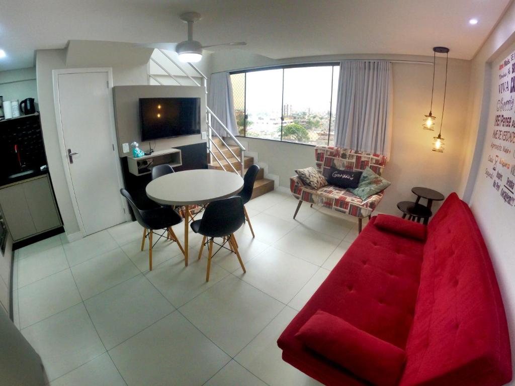 - un salon avec un canapé rouge et une table dans l'établissement Pequeno Paraíso Loft - Praia da Cal, à Torres