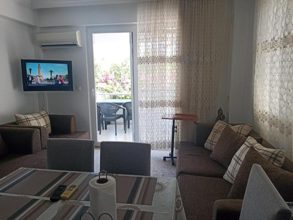 ein Wohnzimmer mit einem Sofa, einem Tisch und einem TV in der Unterkunft 2 Yatak Odalı Daire-Fethiye in Fethiye