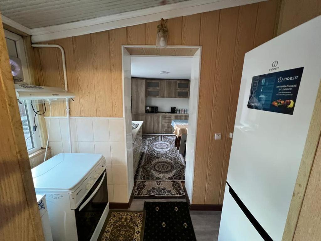 a small kitchen with a white refrigerator and a room at Halal Apartment in Osh