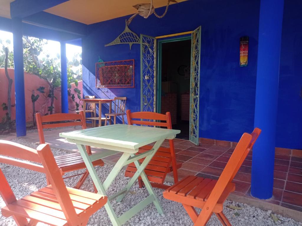 MERMAID HOUSE, casa charmoso, wifi, parking, jardim, cozinha, central CANOA QUEBRADA في أراكاتي: طاولة وكراسي في غرفة ذات جدار أزرق