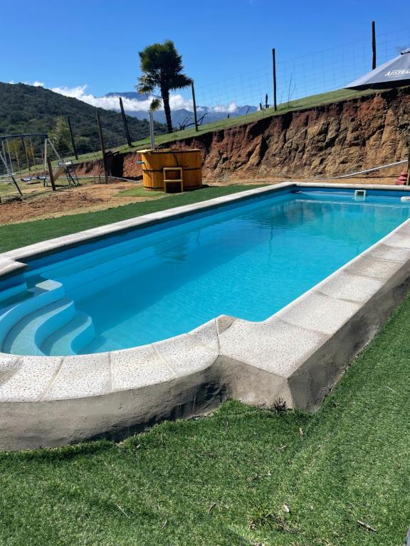 a large blue swimming pool in the grass at Los Quillayes in Melipilla