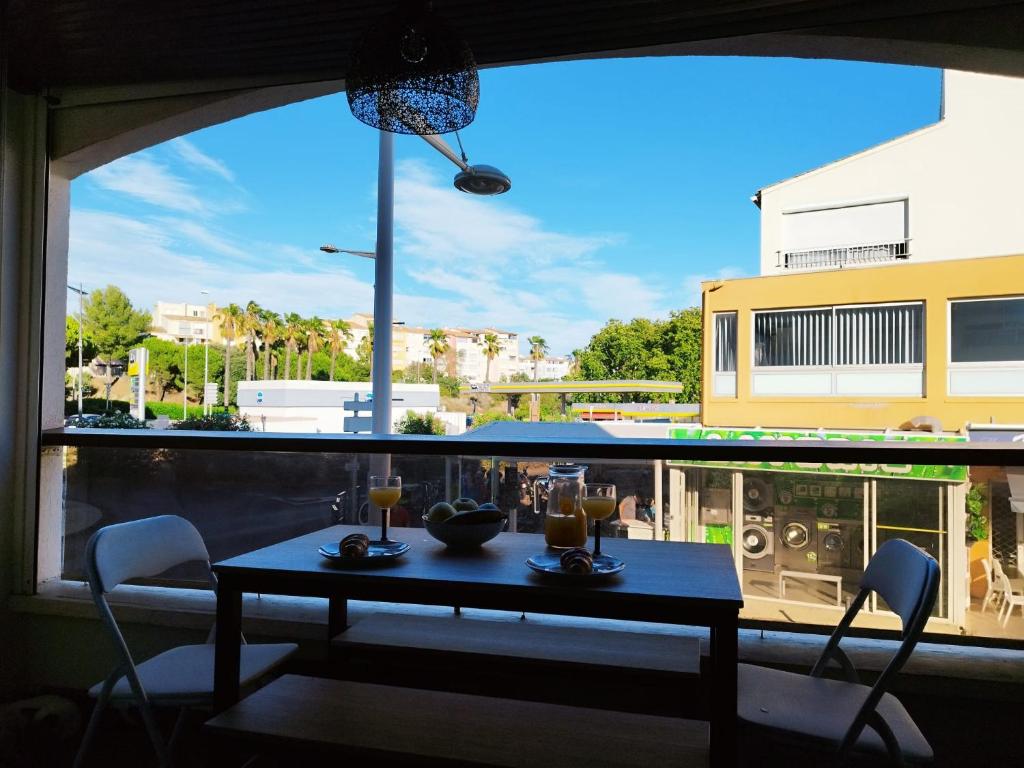 een tafel en stoelen voor een groot raam bij Appartement centre port Cap d'Agde in Cap d'Agde