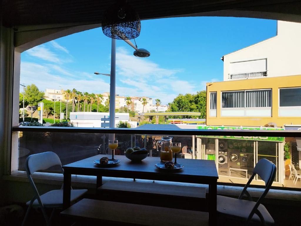 une table et des chaises devant une grande fenêtre dans l'établissement Appartement centre port Cap d'Agde, au Cap d'Agde
