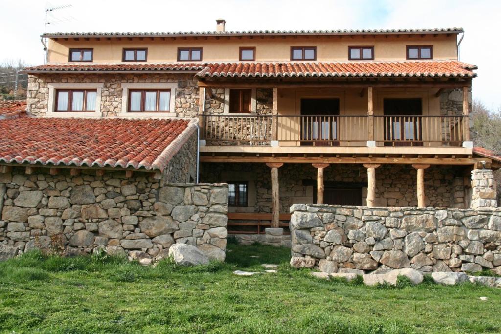 una casa grande con una pared de piedra delante de ella en Casa Rural La Tablilla y La Terraza, en Navalperal de Tormes