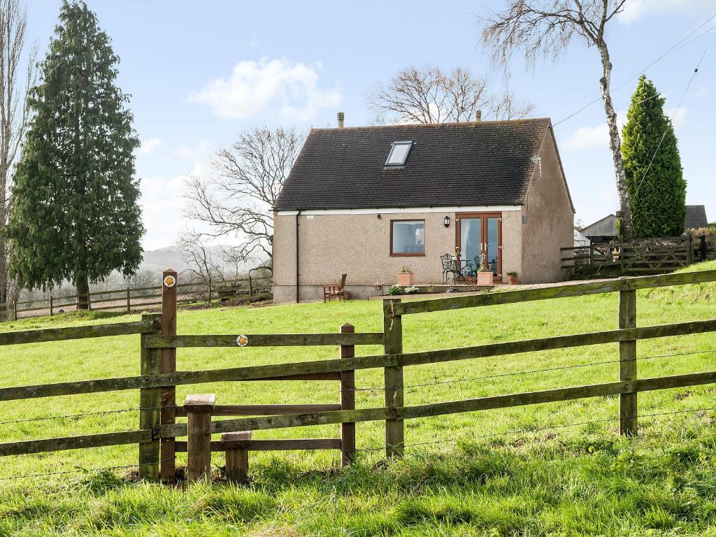 a house in a field behind a fence at Silver Birch Lodge in Horsley