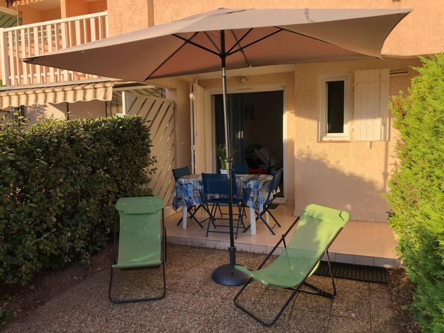 une terrasse avec une table et des chaises sous un parasol dans l'établissement Agay bay see front, à Saint-Raphaël