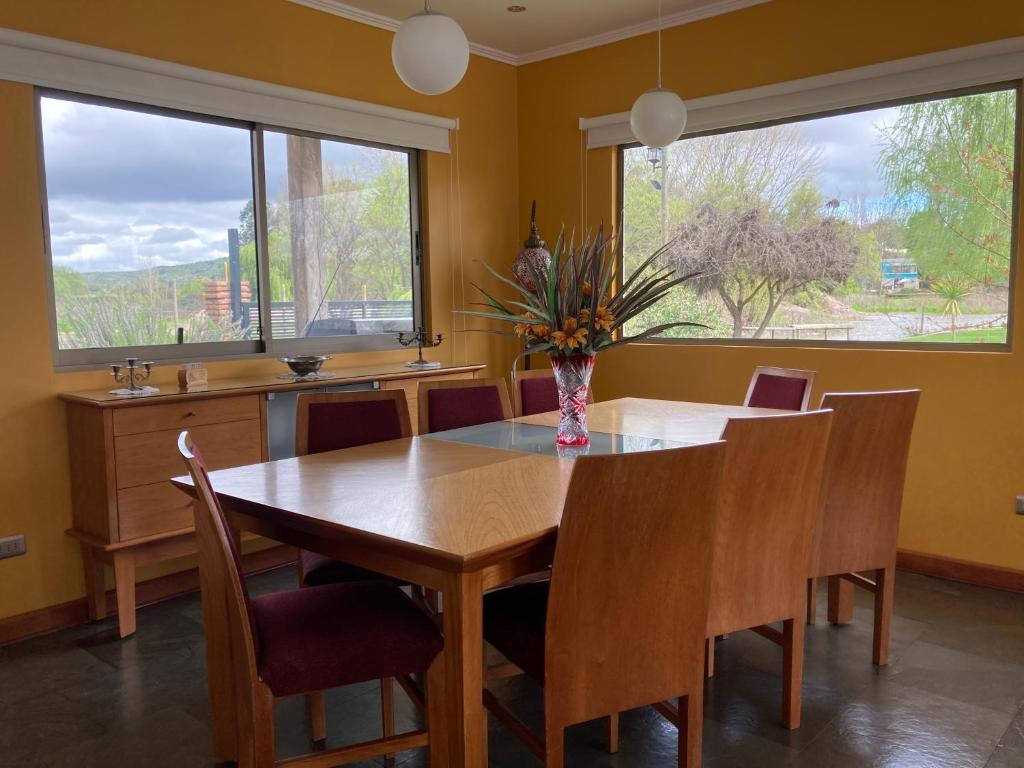 comedor con mesa, sillas y ventanas en Casa en primera línea del Lago Rapel, Punta del Sol, en Las Cabras