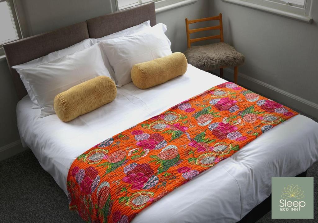 ein Bett mit einer bunten Decke und Kissen darauf in der Unterkunft Sleep Hotel in Worthing
