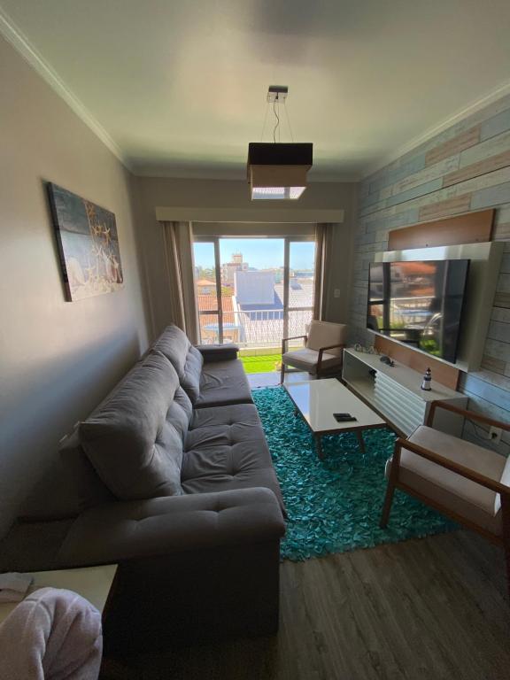 sala de estar con sofá y TV de pantalla plana en Praia da Enseada - apto 3 quartos - a 100m da Praia da Enseada e a 300m da Prainha!, en São Francisco do Sul