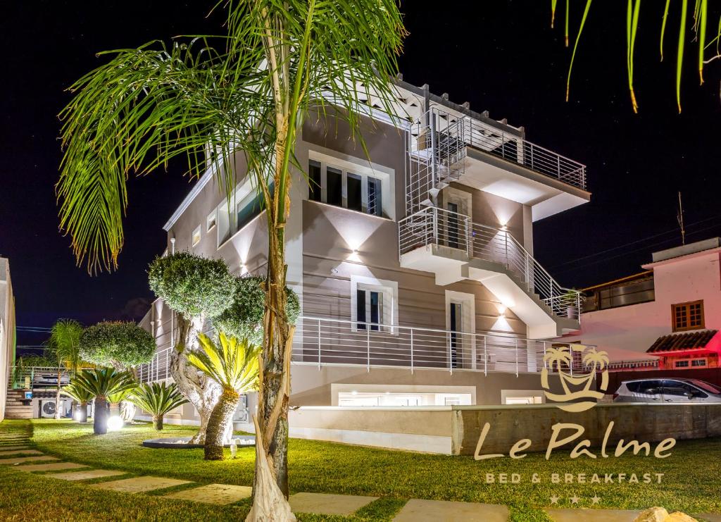 a building with a palm tree in front of it at Le Palme in Terrasini