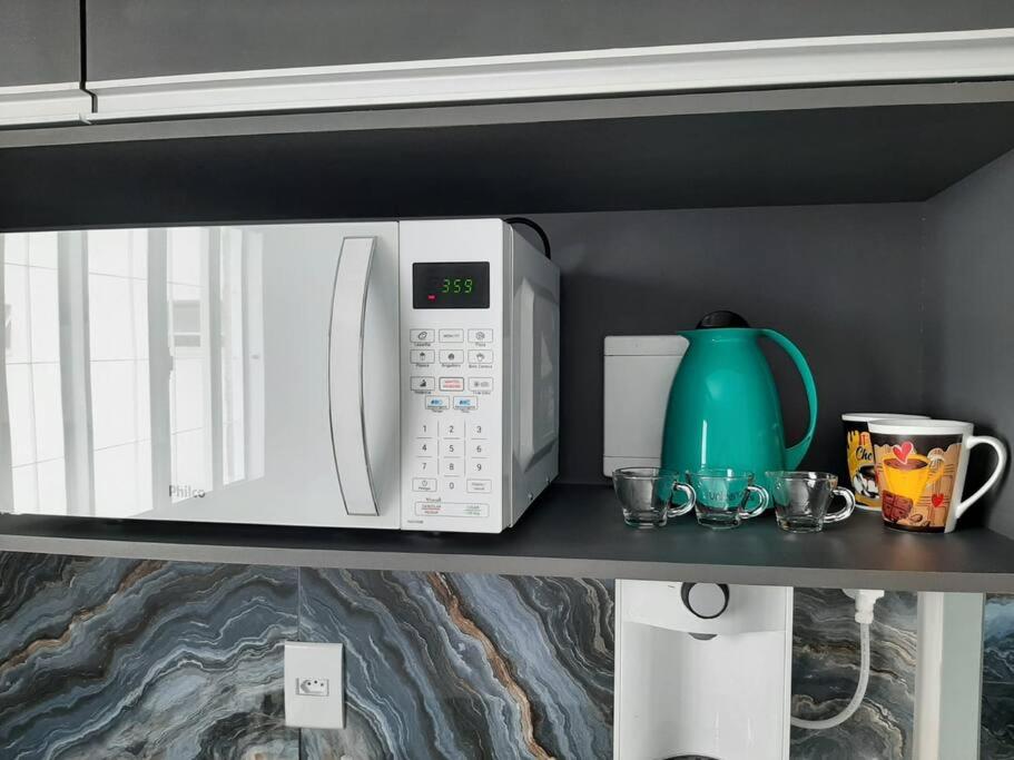 a kitchen counter with two microwaves on a shelf at Luxo e conforto in Goiânia
