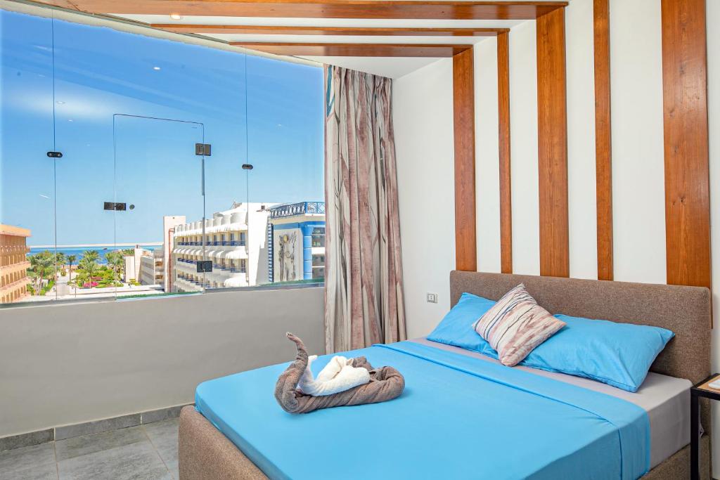 a bedroom with a blue bed with a large window at Bedcoin Hostel in Hurghada