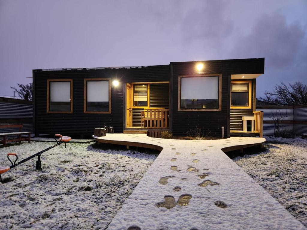 Ein schwarzes Haus mit einem Gang davor. in der Unterkunft Cabaña Bulnes in Puerto Natales
