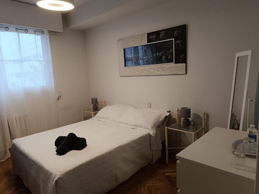 Un dormitorio con una cama con un sombrero negro. en Casa de Mirtha, en Madrid