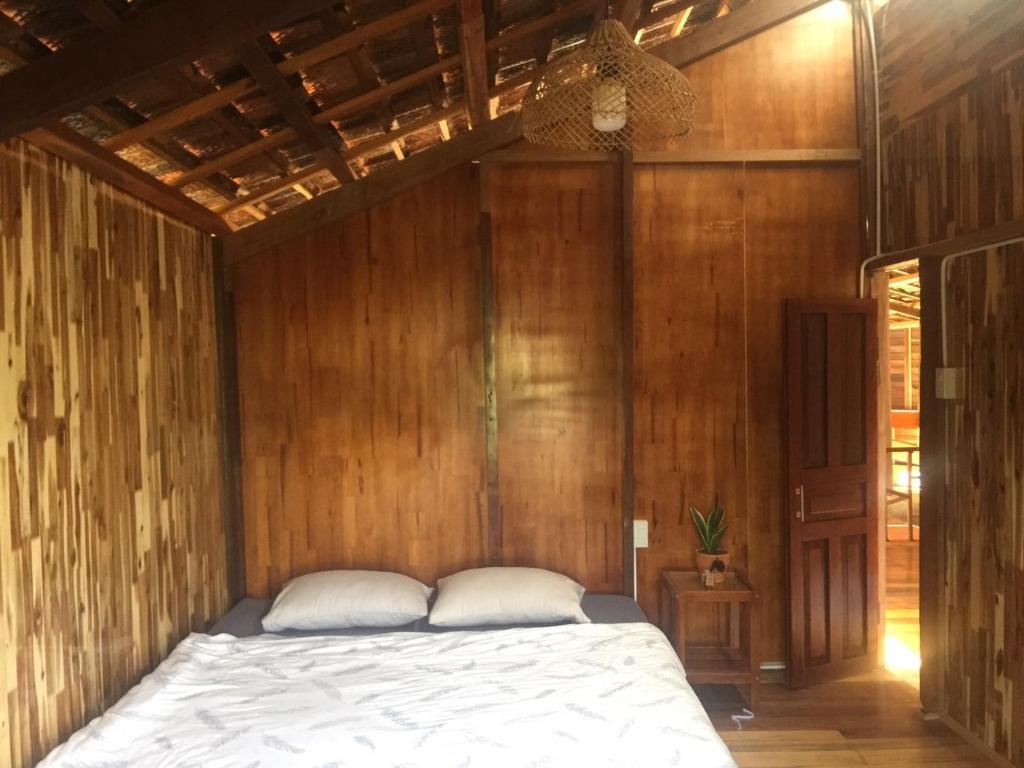 1 dormitorio con 1 cama en una pared de madera en Elon Coffee Farmstay, en Da Lat