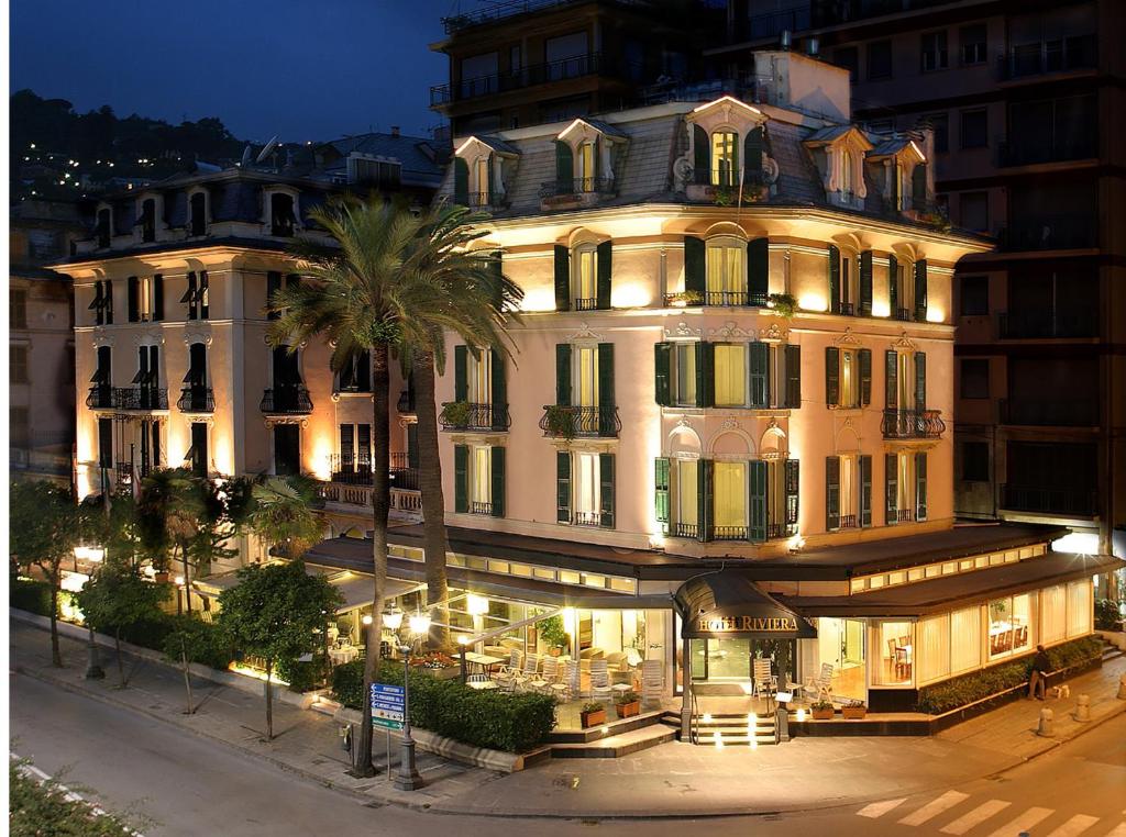 a large white building with a palm tree in front of it at Hotel Riviera in Rapallo