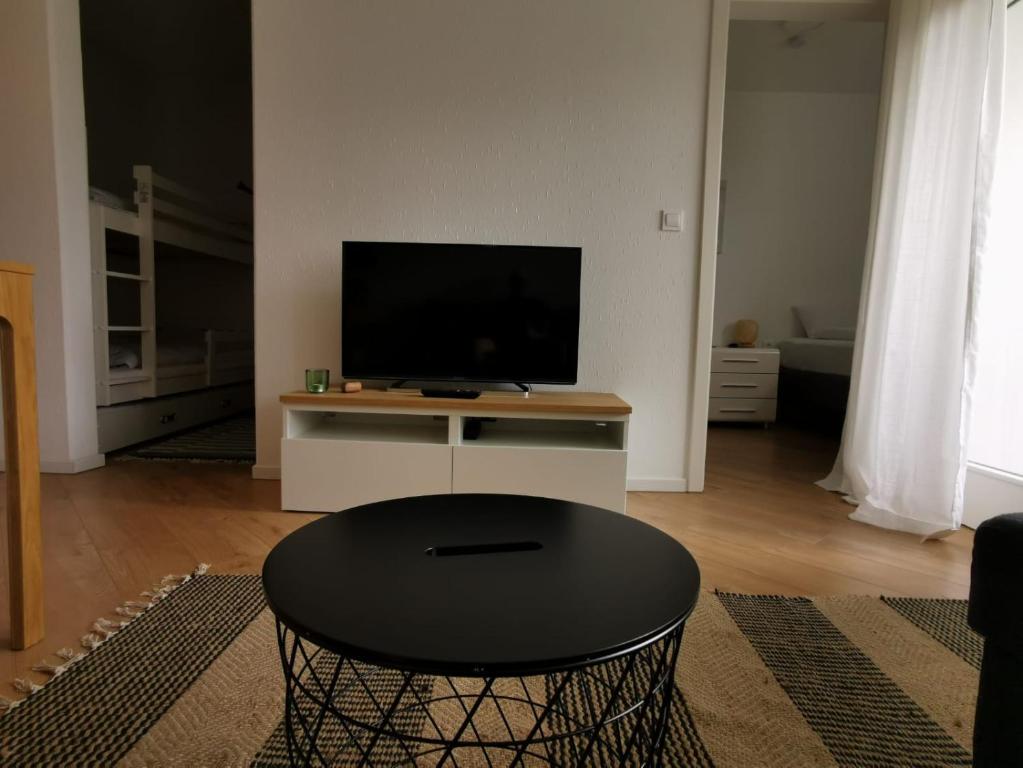 uma sala de estar com uma mesa e uma televisão de ecrã plano em Ferienwohnung Harzlich em Hahnenklee-Bockswiese