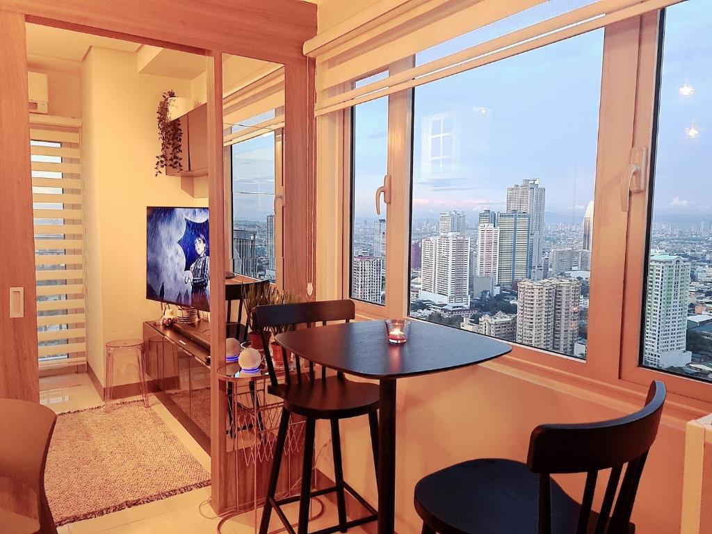 Cette chambre dispose d'une grande fenêtre et d'une table avec des chaises. dans l'établissement Cozy Penthouse Suite w Balcony - Amazing Manila Bay View and City Skyline near MOA, à Manille