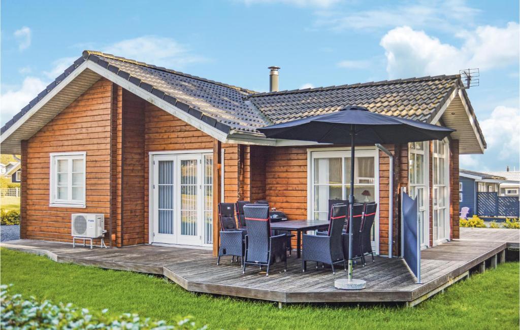 una casa con una mesa y una sombrilla en una cubierta en 3 Bedroom Amazing Home In Juelsminde, en Sønderby
