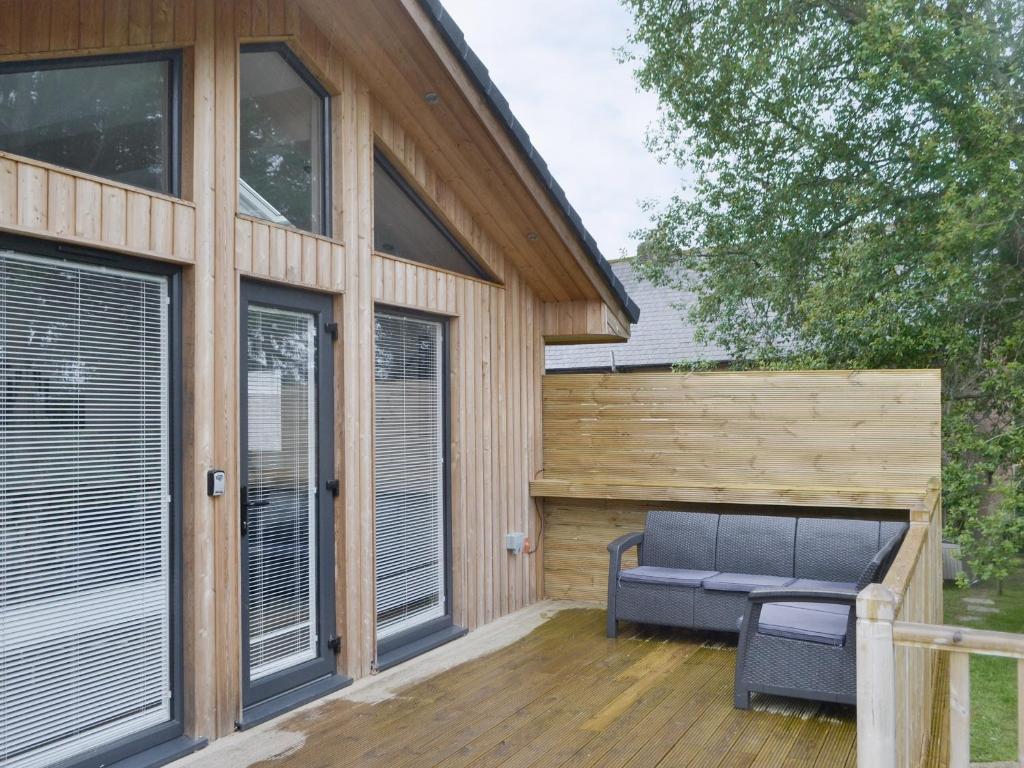 un patio con un sofá azul en una terraza de madera en Little Fawn, en Otterburn