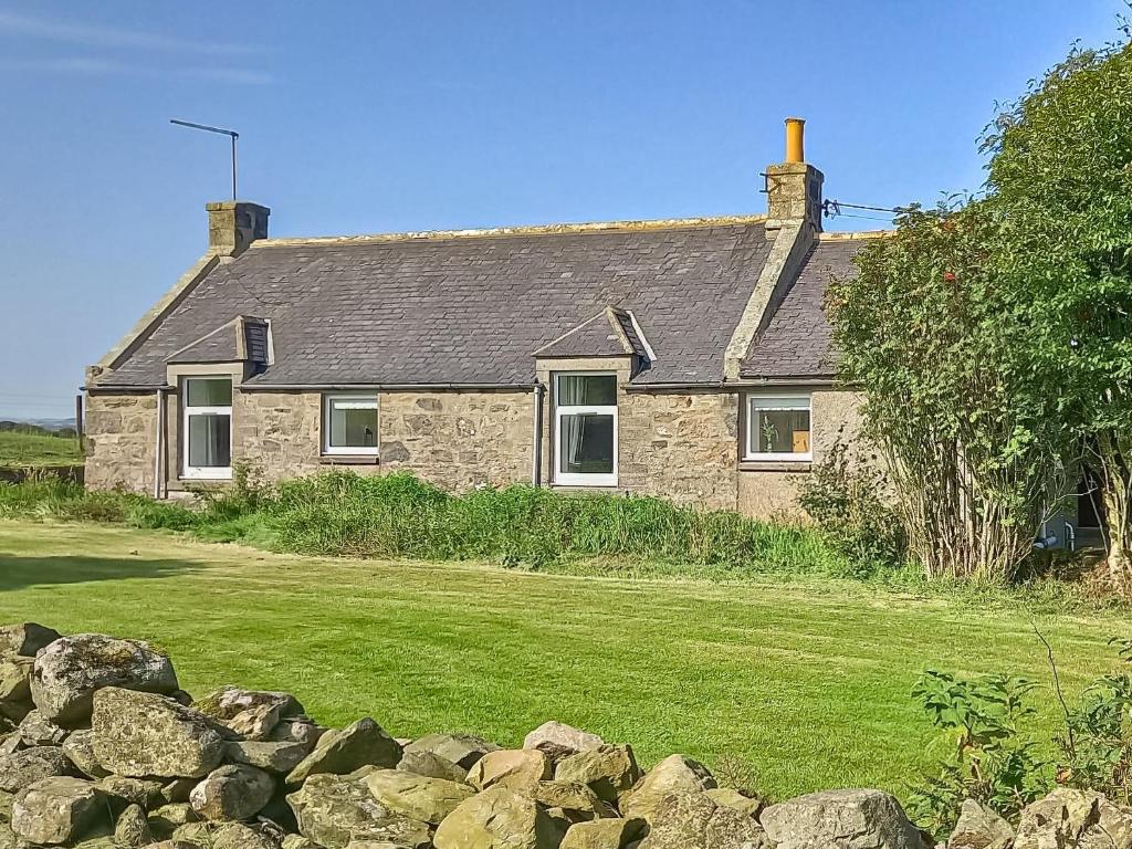 a stone house with a stone wall in front of it at Benwells Holiday Cottage in Maud