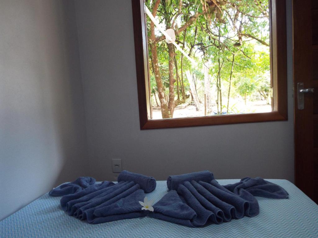 Una cama con tres toallas azules y una ventana. en Casa Bela do Sol, en Isla de Boipeba