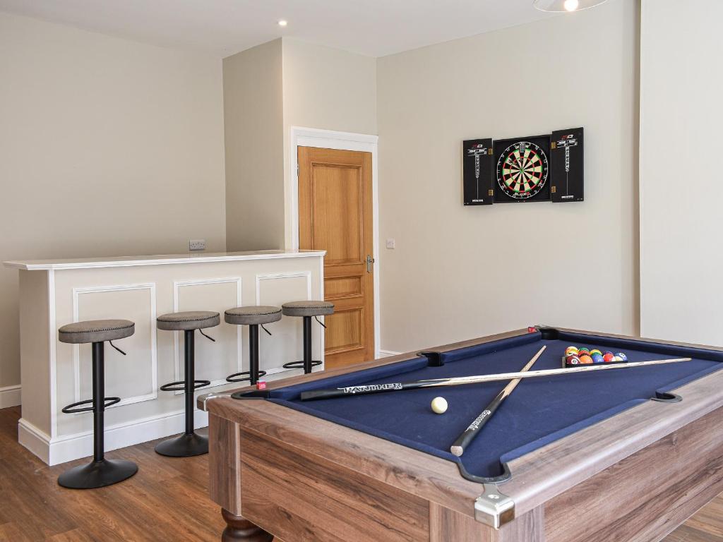 a pool table in a room with bar stools at South Street House in Cockermouth