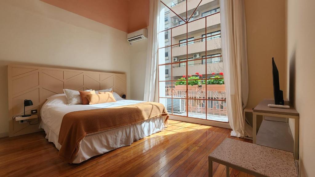 1 dormitorio con cama y ventana grande en Casa Par Grand Suites en Buenos Aires