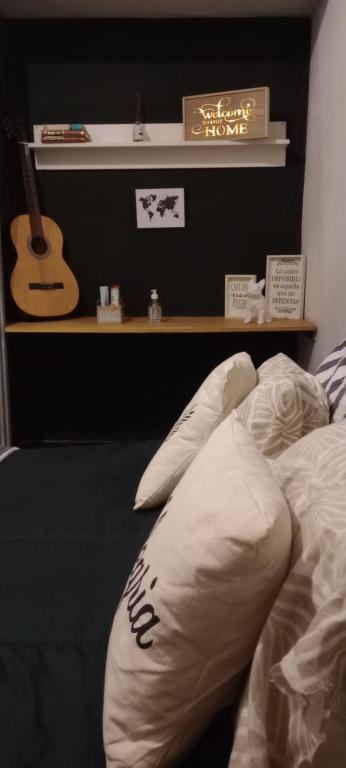1 dormitorio con 1 cama con una guitarra en la pared en La familia en Ezeiza