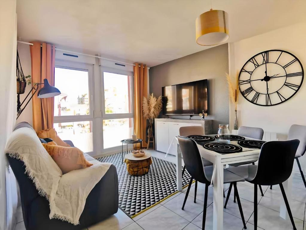 een woonkamer met een tafel en een klok aan de muur bij Appartement T3 Cosy vue port in Lattes