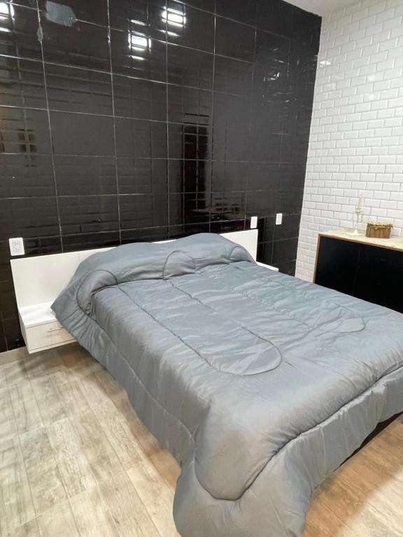 a large bed in a bedroom with a black wall at Espectacular Departamento moderno ,acogedor en vicente López in Vicente López