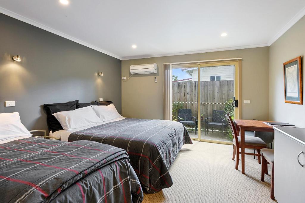 een slaapkamer met 2 bedden, een bureau en een raam bij Motel Strahan in Strahan