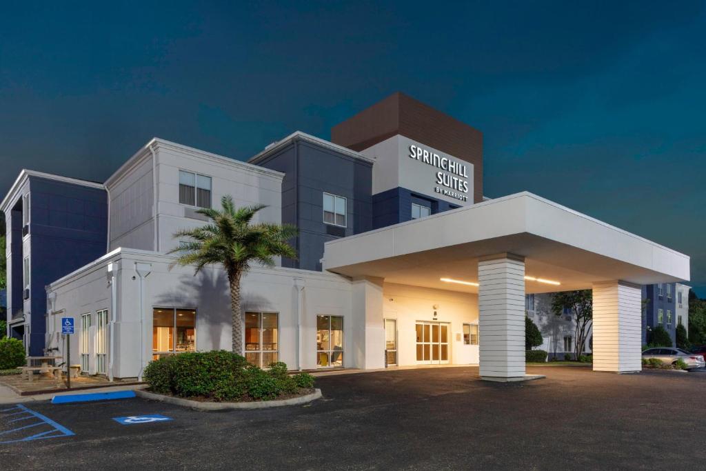 SpringHill Suites by Marriott Baton Rouge South في باتون روج: مبنى ابيض كبير امامه نخلة