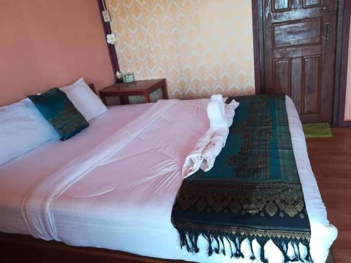 a bedroom with a large bed with pink sheets and a door at Champa Guesthouse in Muang Không
