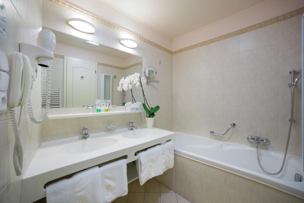 a bathroom with a tub and a sink and a mirror at Interhotel Central in Karlovy Vary