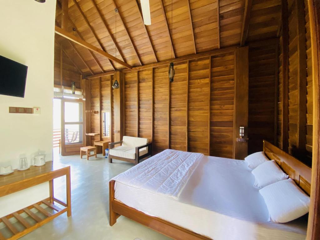 ein Schlafzimmer mit einem großen Bett in einem Zimmer mit Holzwänden in der Unterkunft La Seran Eco Resort in Bandarawela