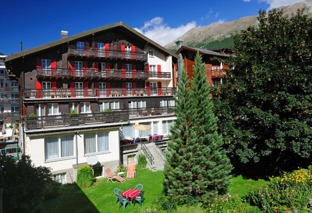 a large building with a tree in front of it at Hotel Alphubel in Zermatt