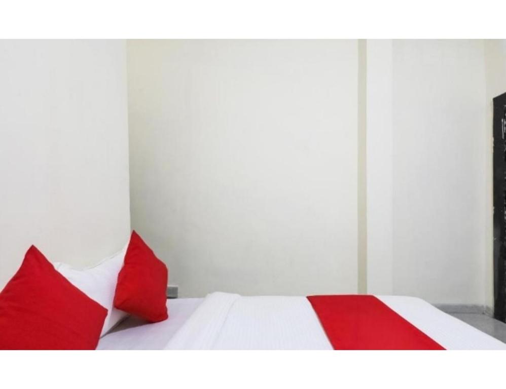 un letto rosso e bianco con due cuscini rossi sopra di Apeksha Hotel, Sanchi a Sānchi