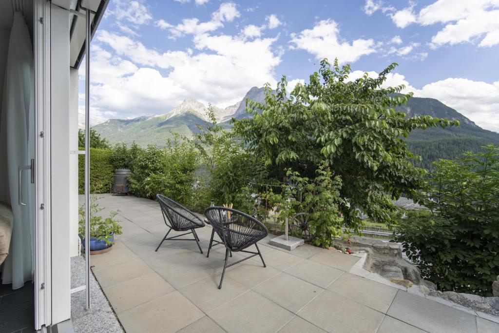 a patio with two chairs and a view of mountains at Chasa Emerita Moderne 3,5-Zimmer Terrassenwohnung mit Panoramablick in Scuol