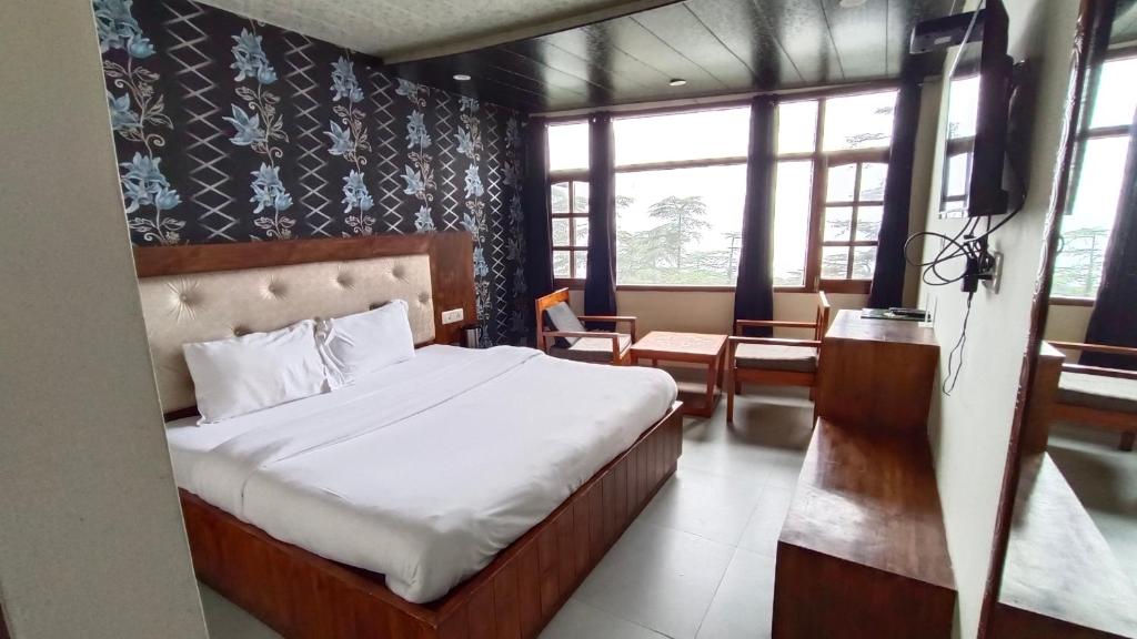 Shimla Royale - Near Mall Road Free Pickup From Railway Station Shimla في شيملا: غرفة نوم مع سرير في غرفة مع نوافذ