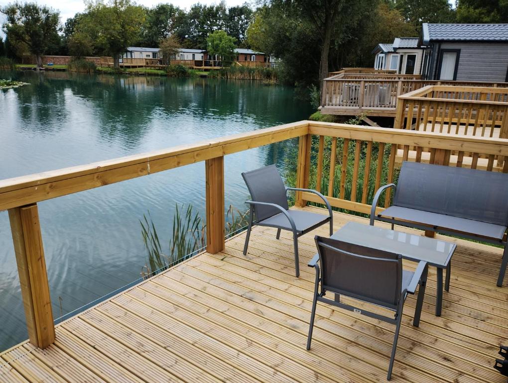eine Terrasse mit 2 Stühlen und einem Tisch auf dem Wasser in der Unterkunft Waterfoot Lodge in Little Habton