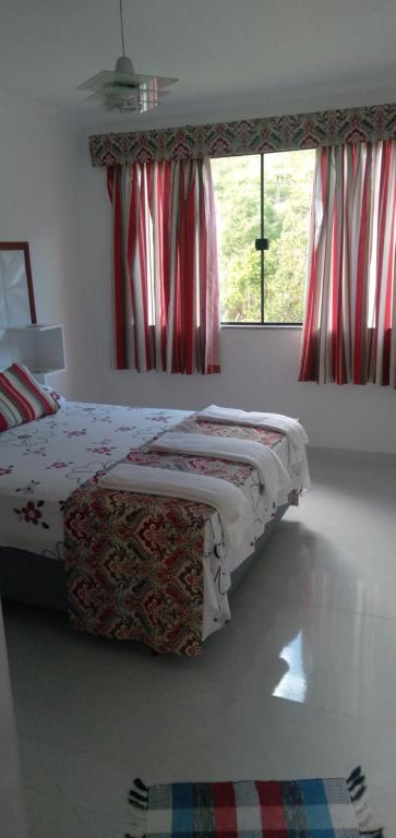 1 dormitorio con cama y ventana en Casa de Campo em Lumiar com corrego ,lareira e churrasqueira en Lumiar