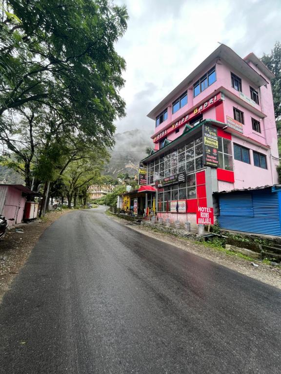 um edifício cor-de-rosa ao lado de uma rua em Hotel Virdh Badri em Joshimath