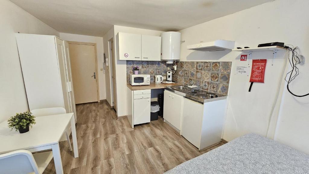 a small kitchen with white cabinets and a refrigerator at Chez Esmara Et Philippe Fourche in Brussels