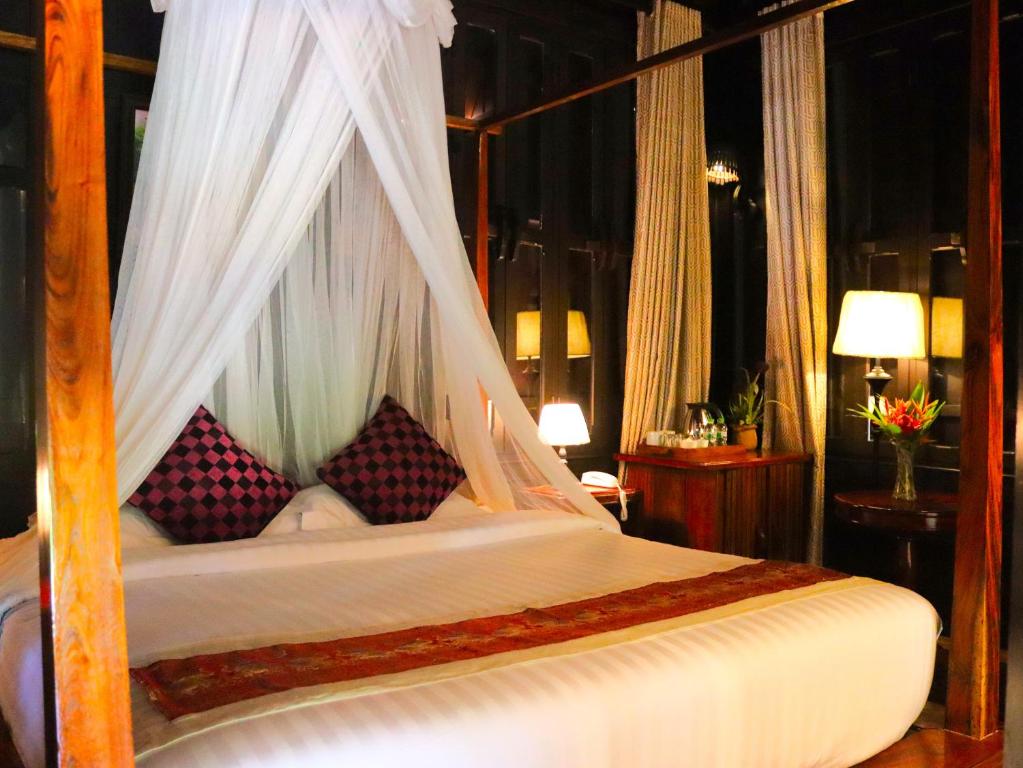 a bedroom with a canopy bed with pillows at Namkhan View Luangprabang Resort in Luang Prabang