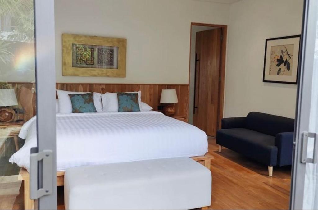 a bedroom with a large white bed and a couch at The Kesari Luxury Villa in Sanur