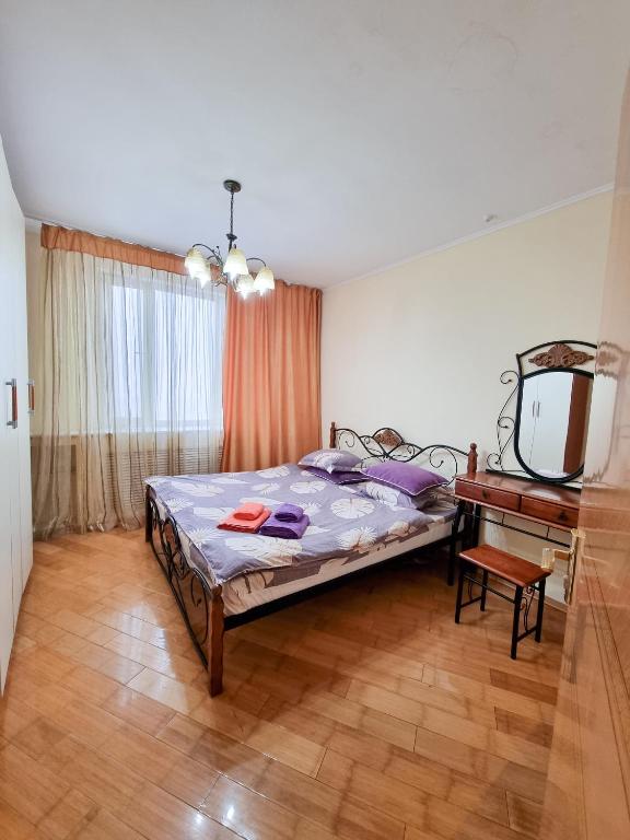 a bedroom with a bed and a table and a mirror at Квартира in Astana