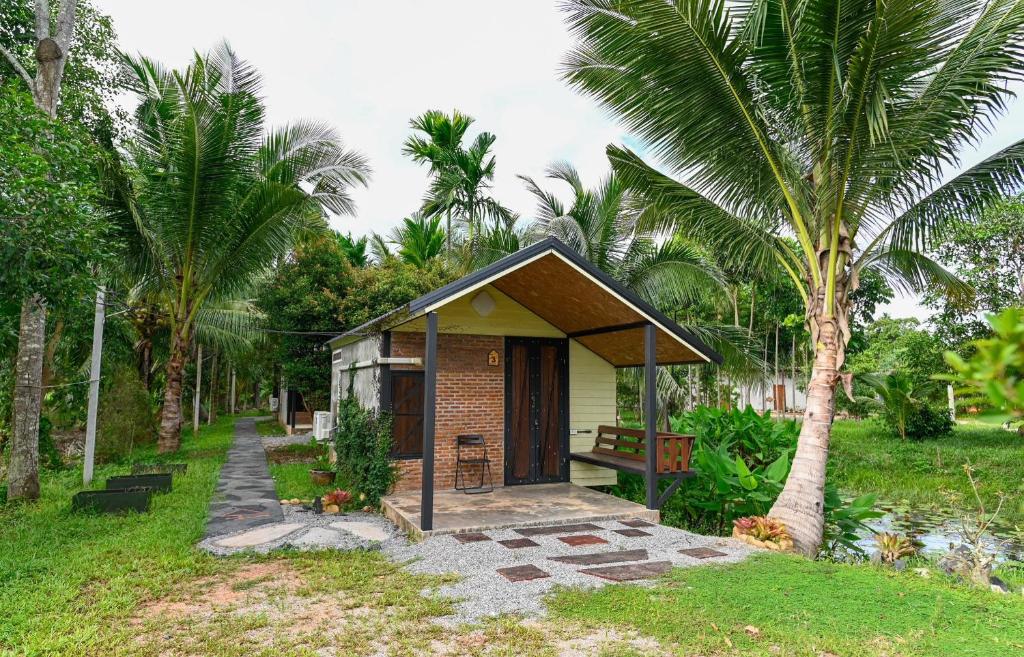 une petite maison dans un jardin planté de palmiers dans l'établissement เป่าฟู่เฮ้าส์ Bao Fu's House, à Chumpon
