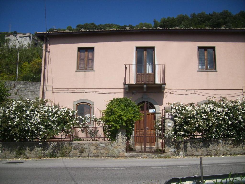 uma casa cor-de-rosa com flores brancas à frente. em Casa Vacanze Liperni em Raccuia