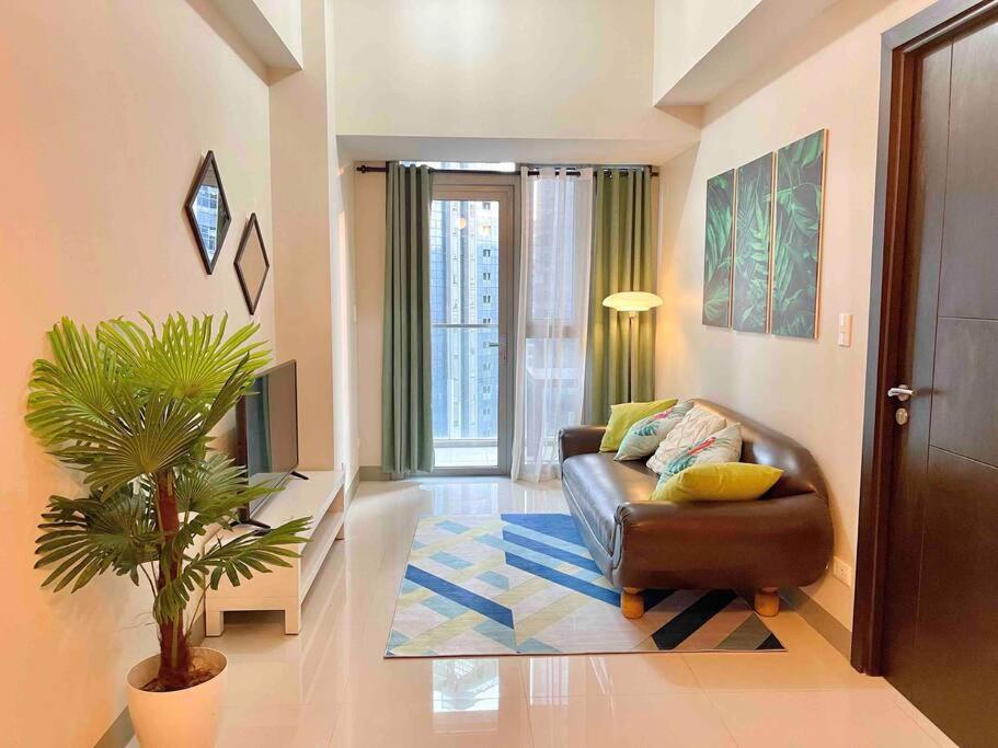 ein Wohnzimmer mit einem Ledersofa und einer Pflanze in der Unterkunft Tropical 1BR Uptown Parksuites BGC, 200mbps Smart TV in Manila